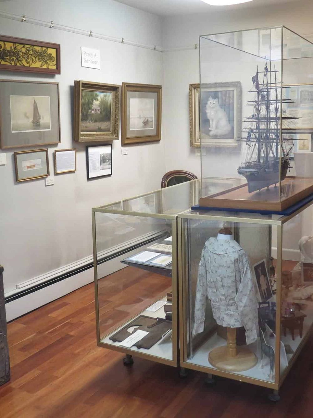 Vintage art gallery with framed paintings, ship model, and historical artifacts for museum exploration.