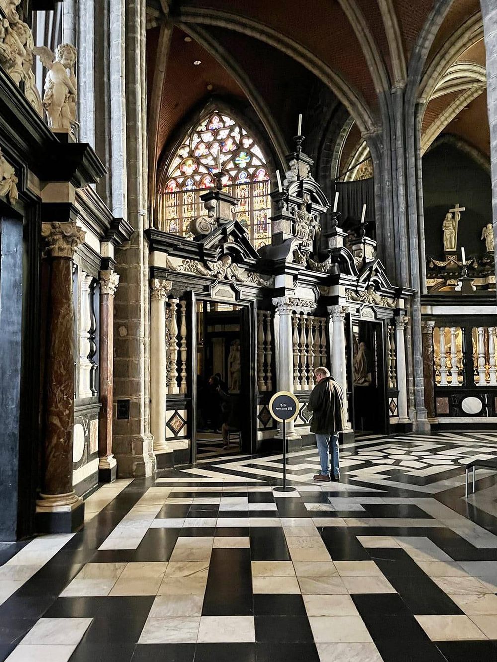 Intricate religious artwork inside a historic cathedral with stained glass windows and ornate architecture.