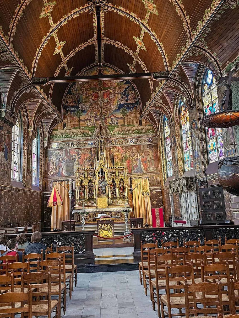 Intricate church interior with stained glass windows and religious artwork, showcasing historic religious architecture.