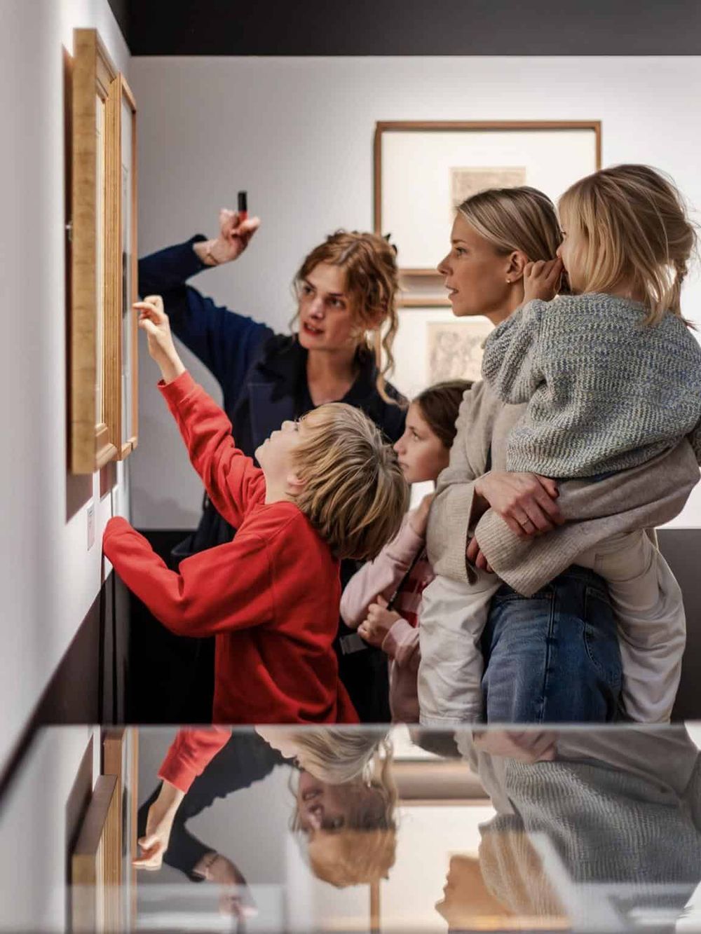 Kids and adults exploring art pieces at an art gallery, engaging in educational activities and art appreciation.