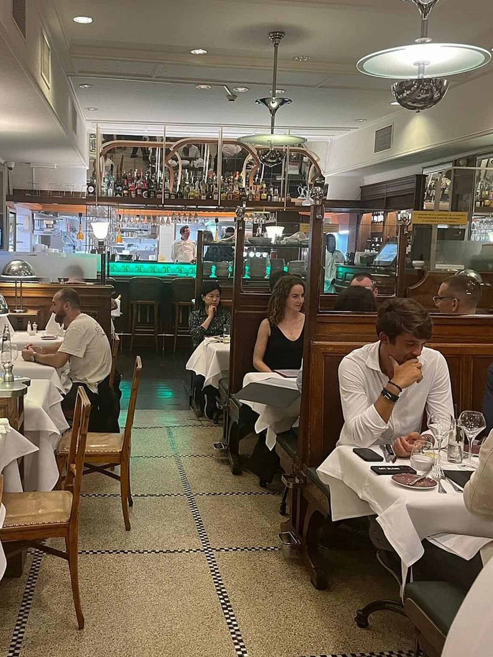 Elegant restaurant interior with customers enjoying gourmet meals and a stylish bar area. Perfect for fine dining experiences.