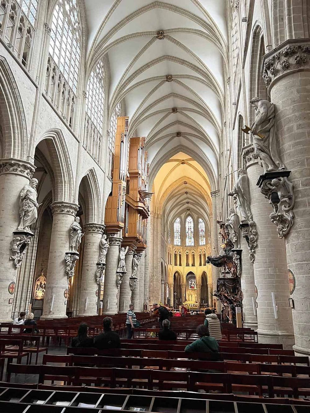 Intricate Gothic cathedral interior with soaring arches, ornate sculptures, and stained glass windows, showcasing historic church architecture.