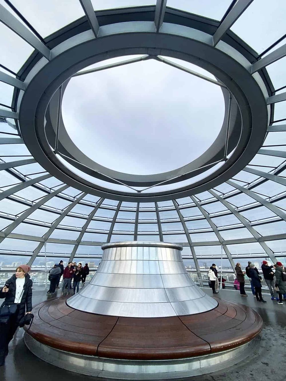 Vast glass observation deck with modern spiral design, city views, and visitors exploring the structure.