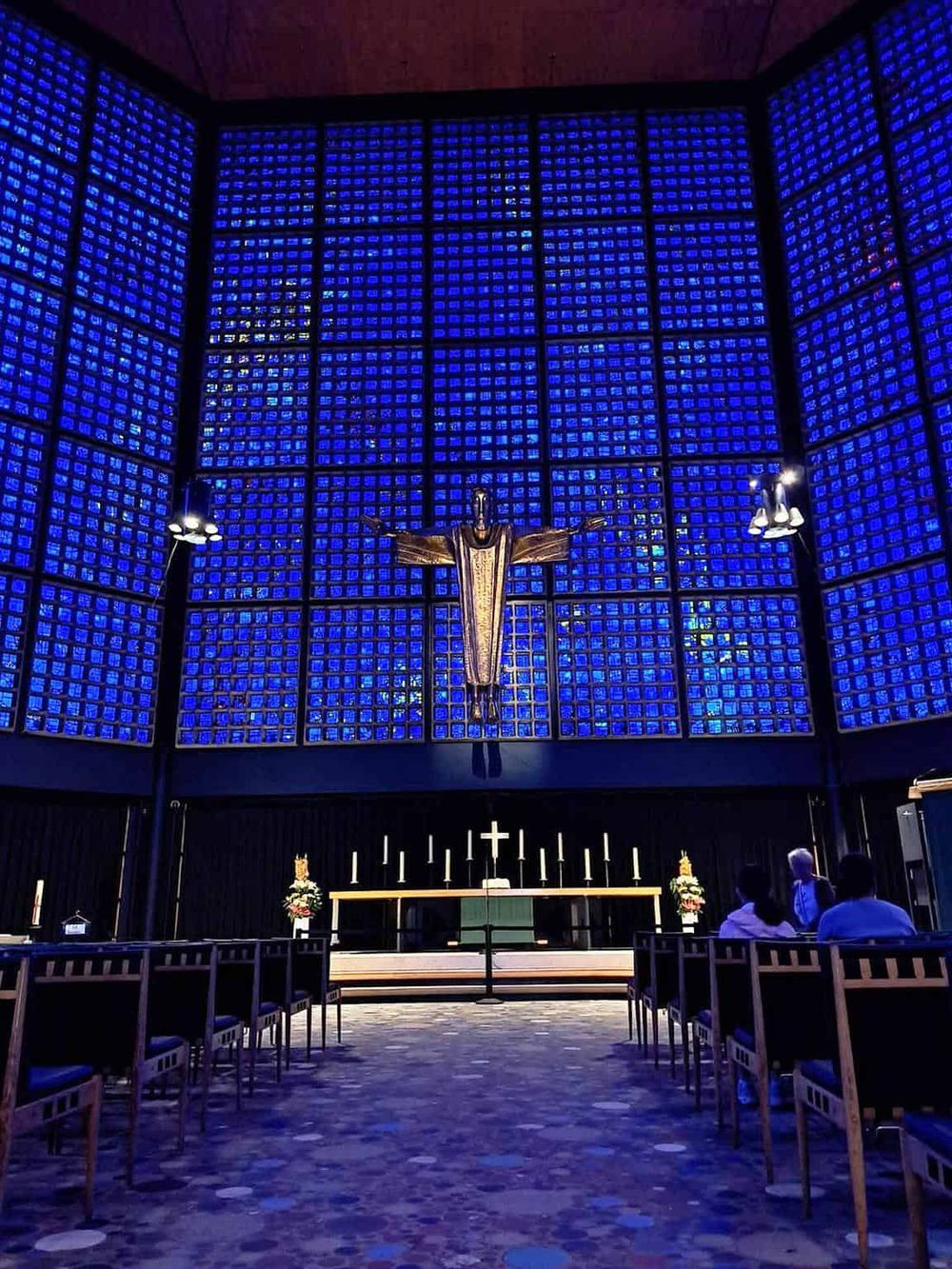 Colorful church interior with vibrant blue stained glass windows and modern religious decor.