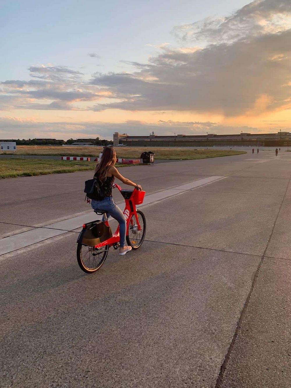 Bike rider at sunset outside airport with QuestForDirections signage, showcasing airport navigation solutions.