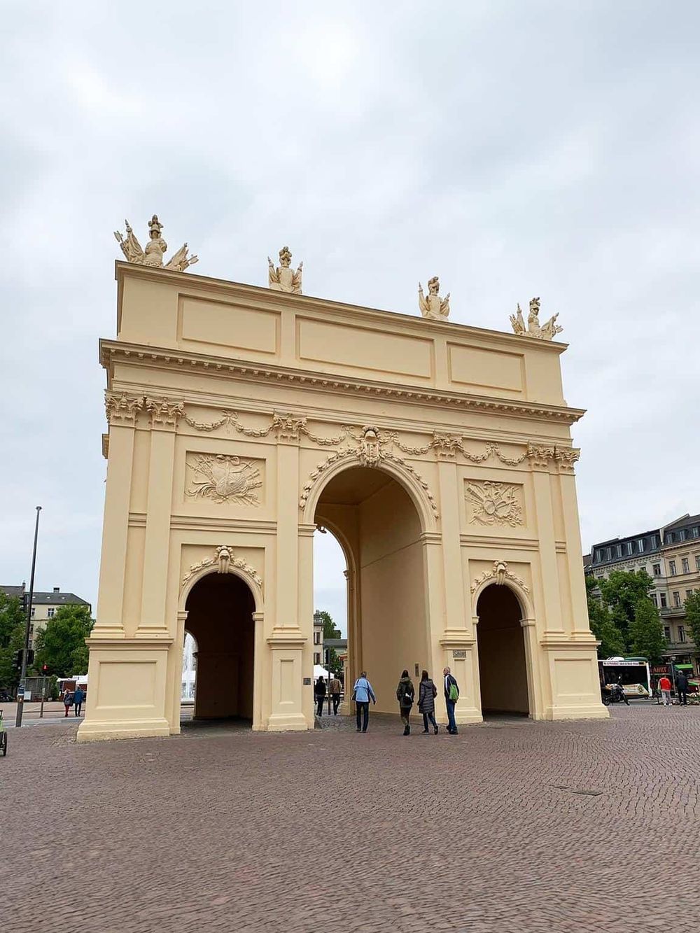 Majestic triumphal arch in Paris, France, with ornate sculptures and classical architecture. Visitors gather under its grand arches.