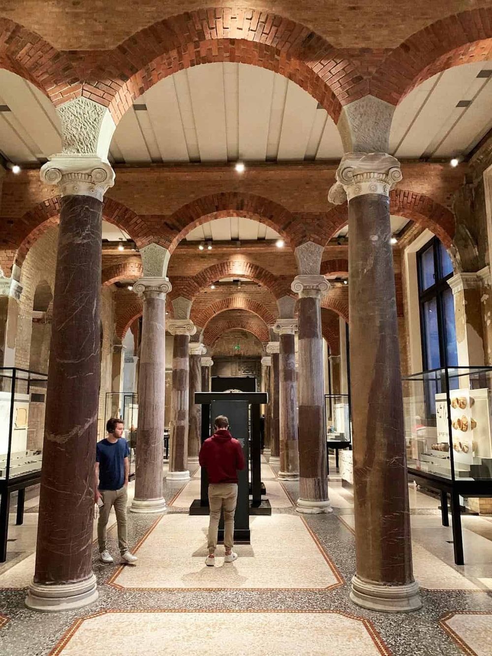 Stunning interior of historic museum with marble columns and arches, showcasing cultural and artistic exhibits.
