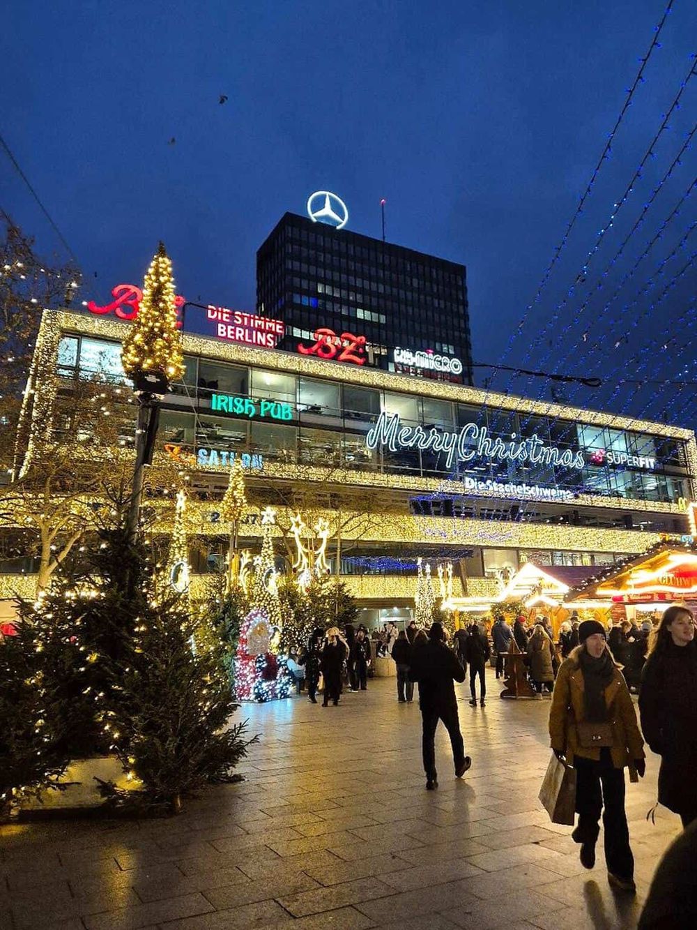 Festive Christmas market with illuminated decorations and crowds at night, showcasing holiday spirit in Berlin.