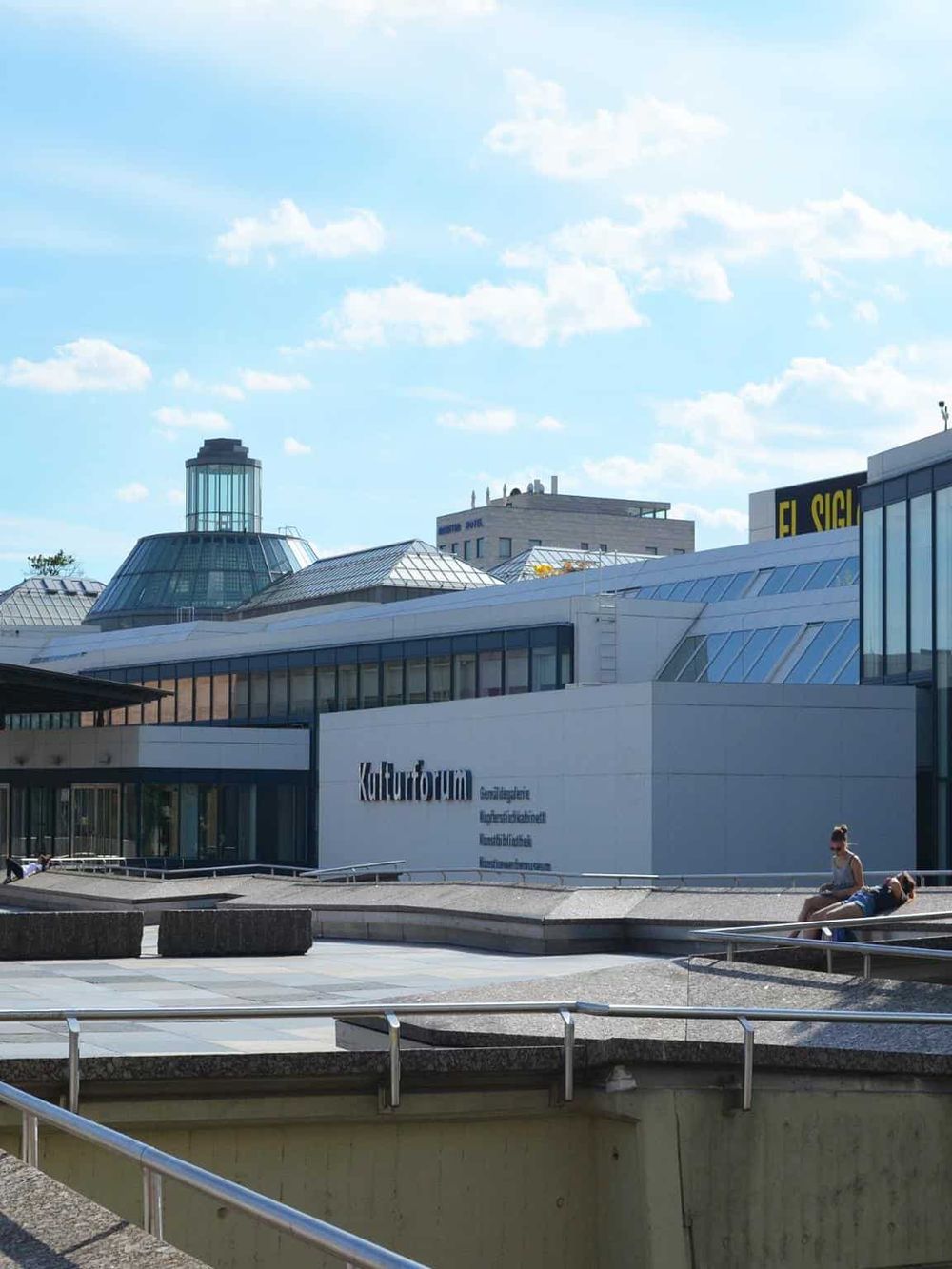 Modern cultural center with innovative architecture in an urban setting under a bright blue sky.