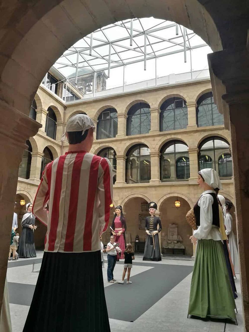 Colorful historical mannequins in a glass-roofed atrium at Quest for Directions, showcasing cultural exhibits and museum displays.