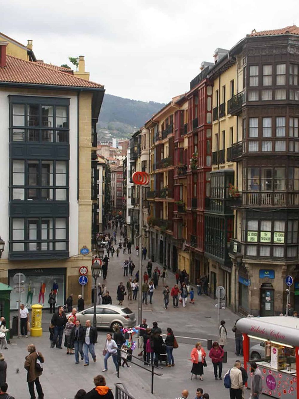 Bustling city street with colorful buildings, shops, and pedestrians in a popular tourist destination.