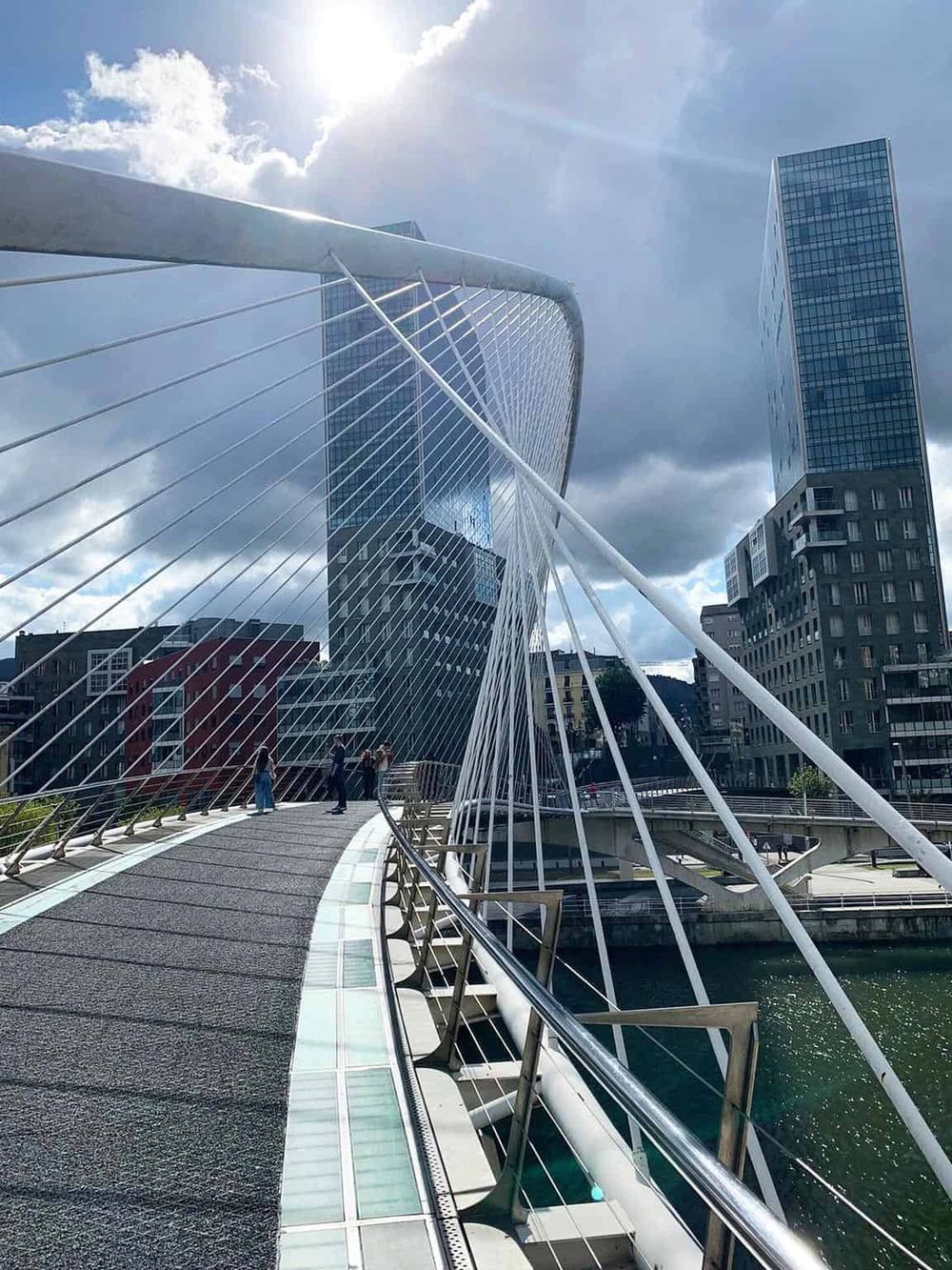 Modern cityscape with innovative architecture and a pedestrian bridge in a bustling urban area.