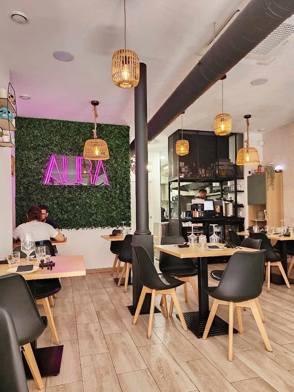 Bright interior of Aura restaurant with modern decor, wooden furniture, and ambient lighting.