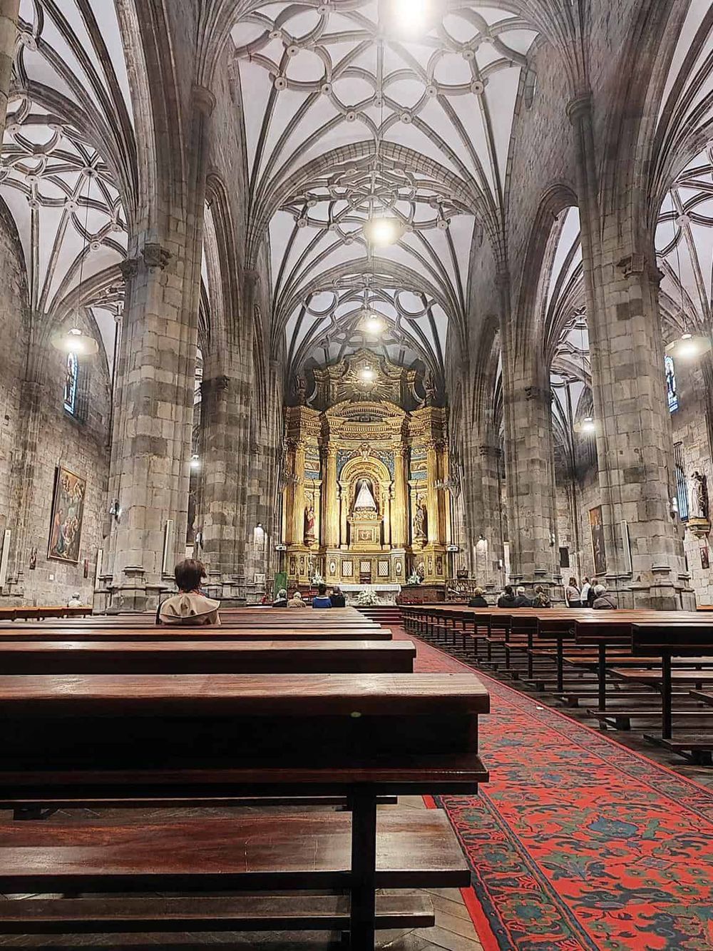 Ancient Gothic cathedral interior with soaring vaults and ornate altar, showcasing historic religious architecture.