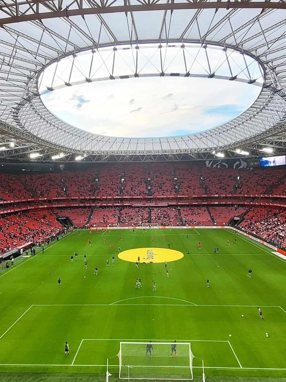 1. Modern stadium with a partially open roof and vibrant red seating areas for soccer fans.
