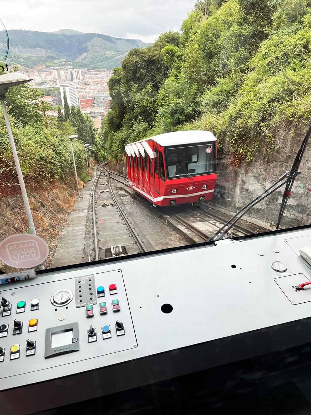 Modern funicular railway car traveling through scenic hillside in an urban environment, emphasizing transportation and city views.