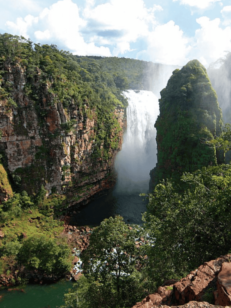 Vast waterfall surrounded by lush green cliffs and forest, scenic nature landscape, QuestForDirections.
