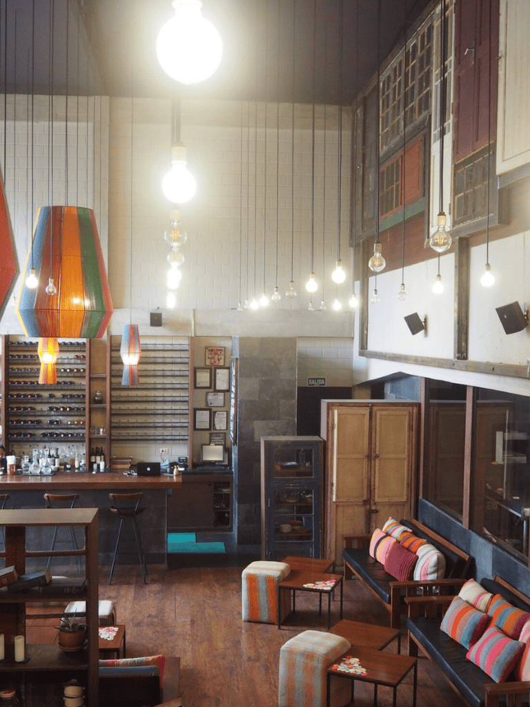 Cozy coffee shop interior with colorful pendant lights, wooden furniture, and comfy seating.