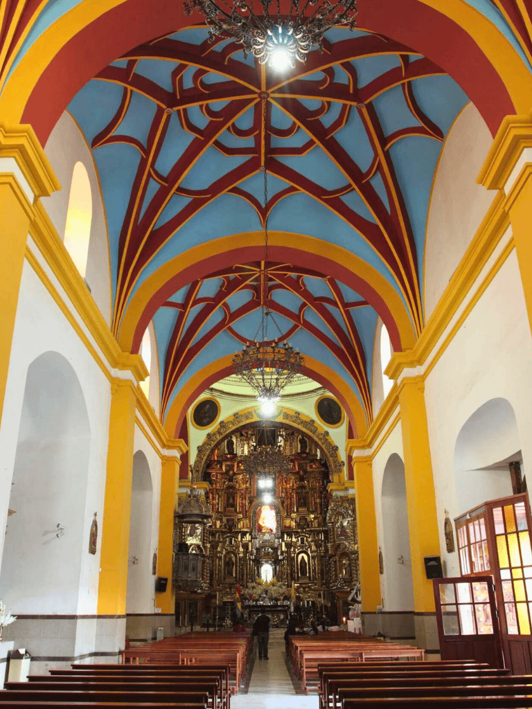 Colorful church interior with ornate altarpiece and vibrant ceiling design.