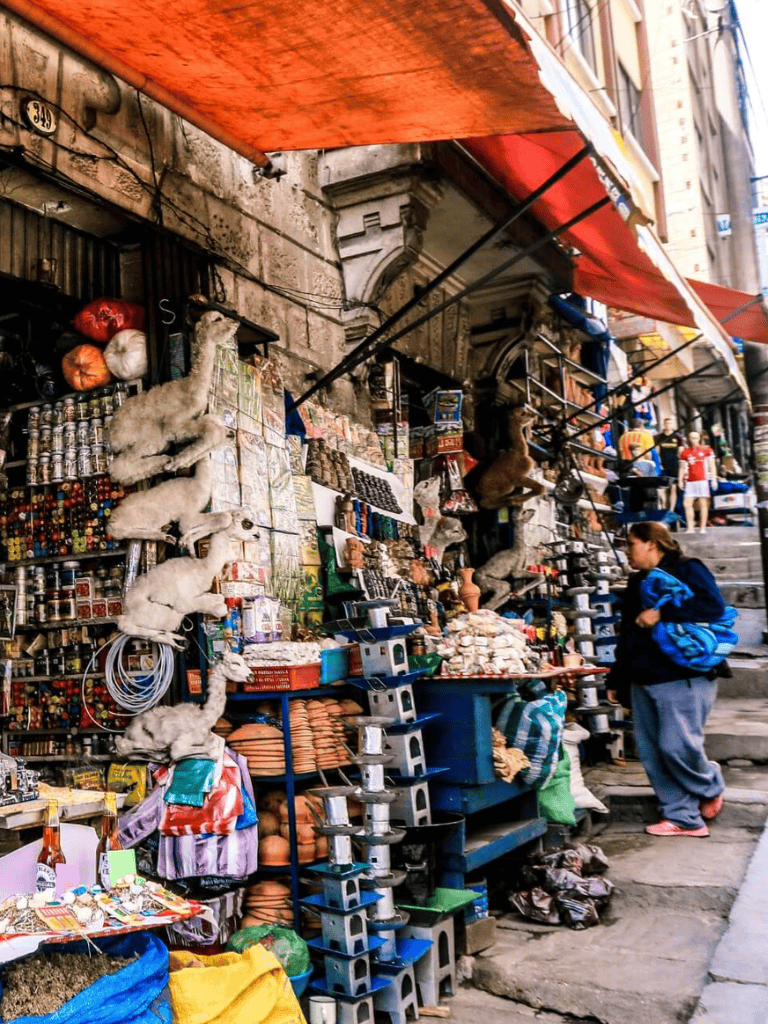 Colorful street market stall with souvenirs, plush toys, and snacks on a bustling urban street.