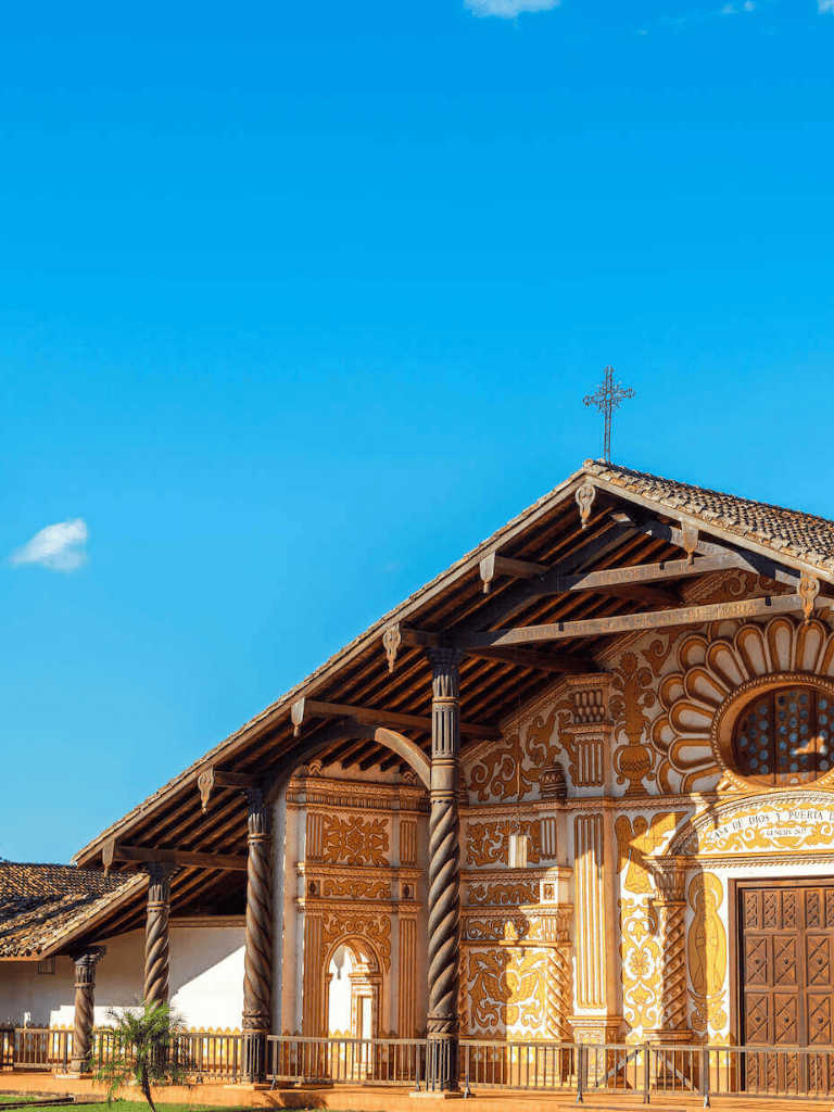 Colorful preserved church facade with intricate woodwork and religious symbols under clear blue sky.
