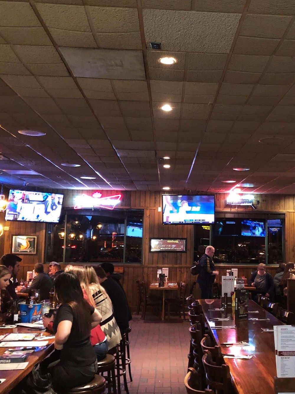 Vibrant sports bar with multiple TVs, friendly patrons, and a lively atmosphere, perfect for watching games and dining out.