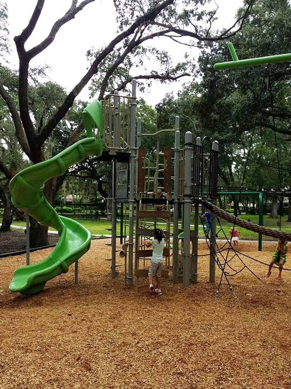 Colorful children's playground with slides, climbing structures, and swings in a park setting.
