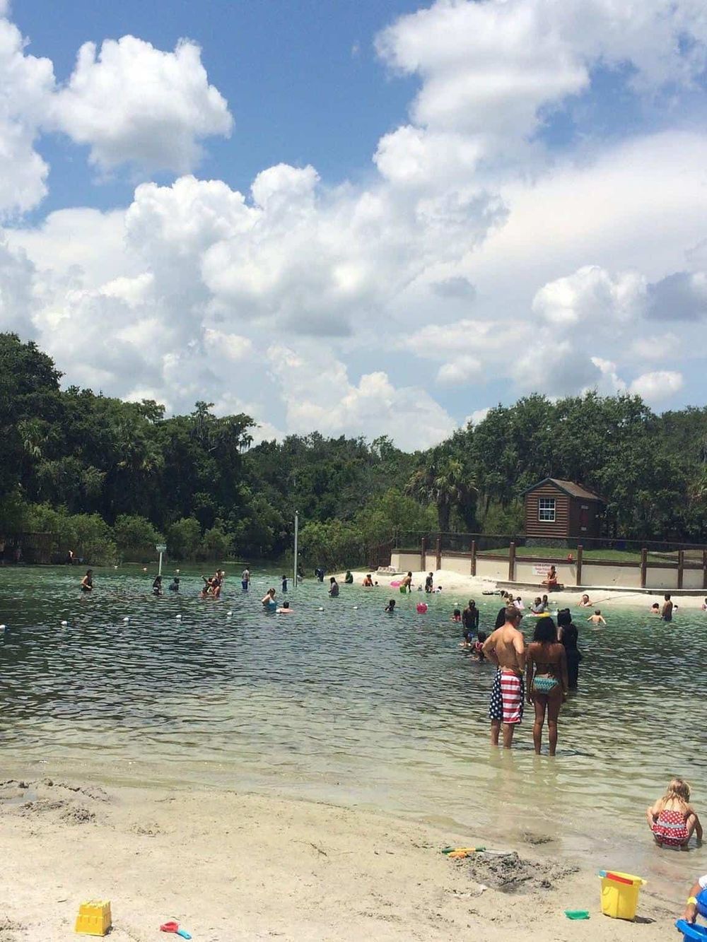 Scenic outdoor water park with families swimming and relaxing in a natural lagoon setting.