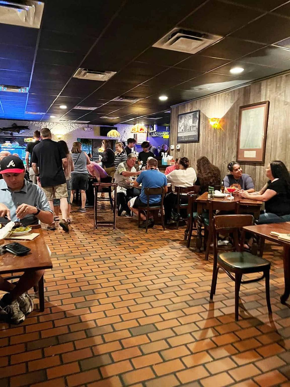 Bustling restaurant interior with diverse diners enjoying meals and drinks, warm lighting, and cozy wooden decor.