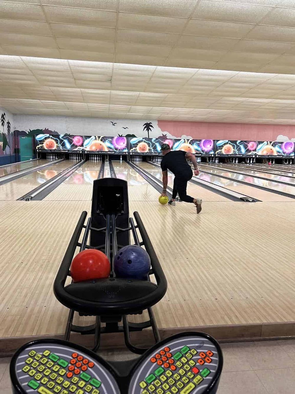 Bowling alley with colorful pins and a player about to roll the ball, featuring a modern, family-friendly entertainment setting.
