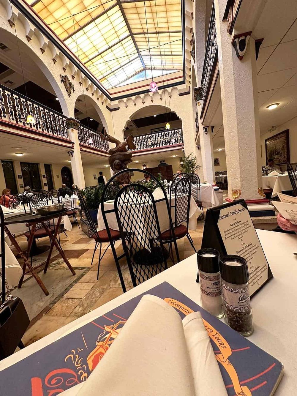 Elegant restaurant interior with high glass ceiling, decorative columns, and modern furnishings for fine dining.