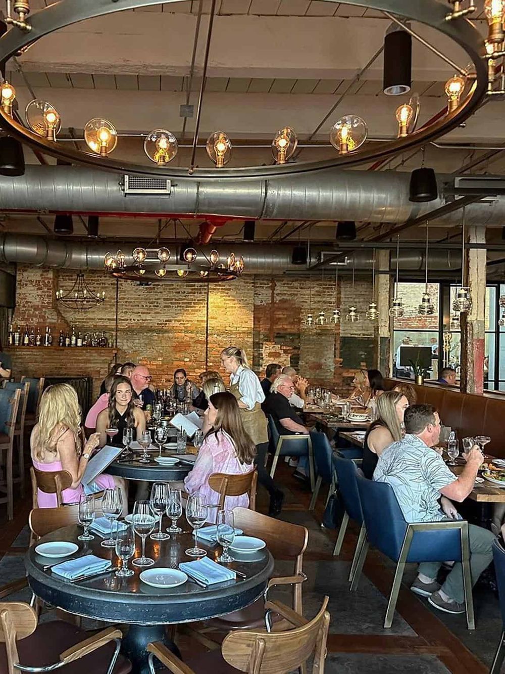 Elegant modern restaurant interior with exposed brick walls and industrial lighting.