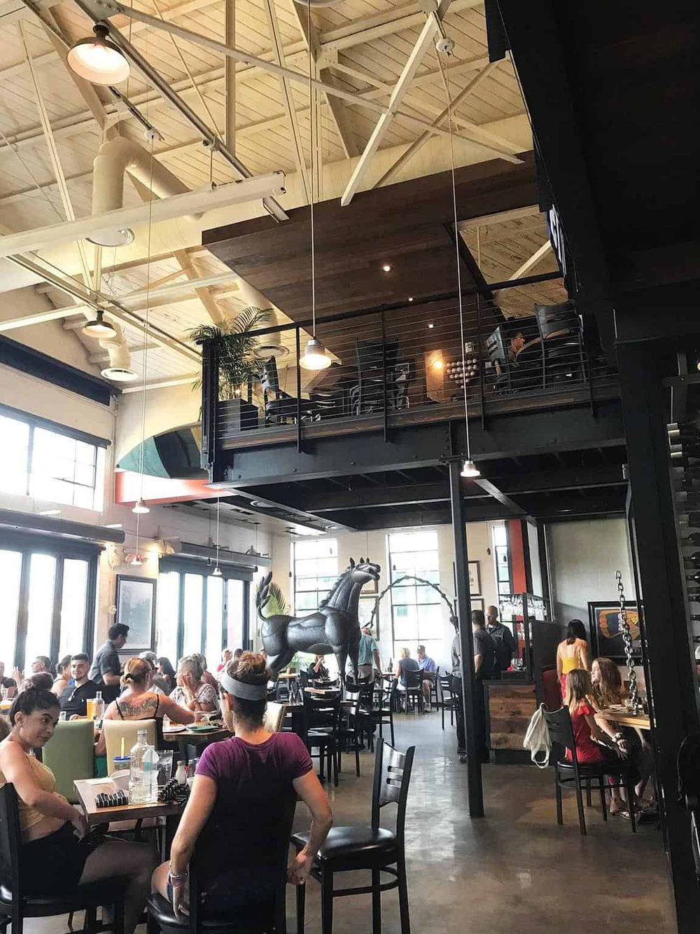 Bright, modern indoor dining space with high ceilings, large windows, and contemporary decor.