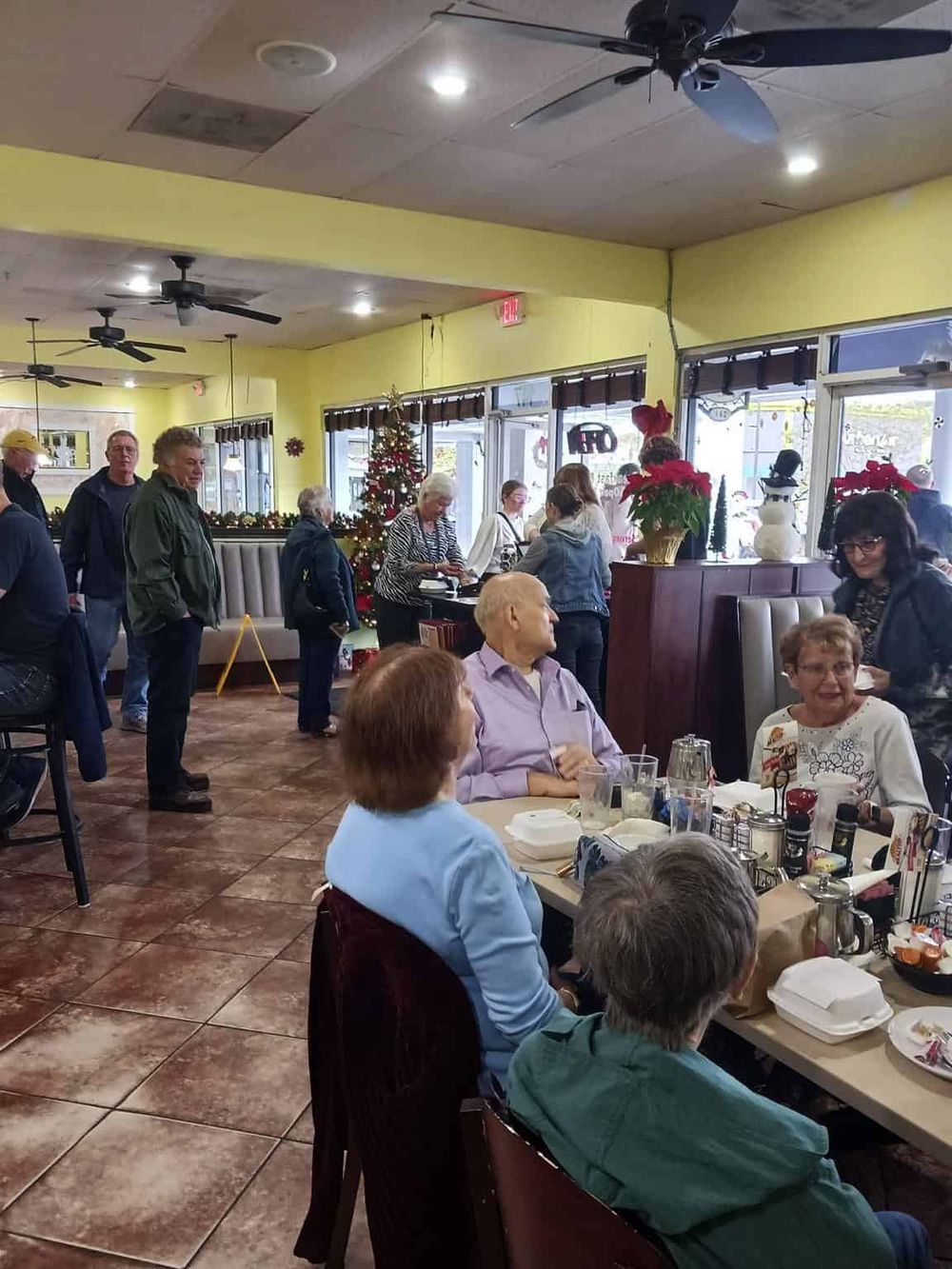 Festive holiday gathering at a restaurant decorated with Christmas ornaments and poinsettias.
