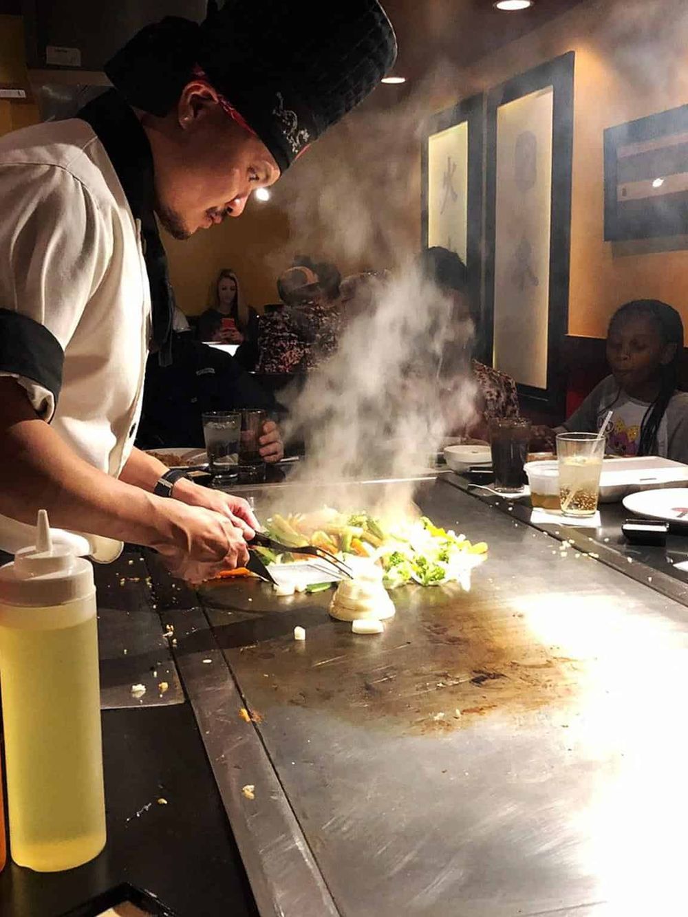 Vibrant teppanyaki chef cooking colorful vegetables at a Japanese restaurant, creating an engaging dining experience.