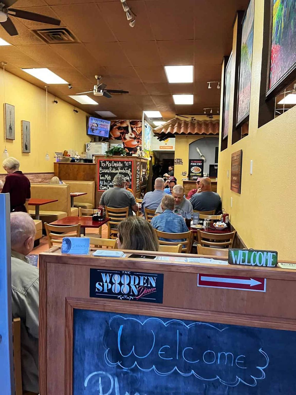 Cozy family restaurant interior with diners enjoying meals, warm yellow walls, and welcoming atmosphere, perfect for casual dining experiences.