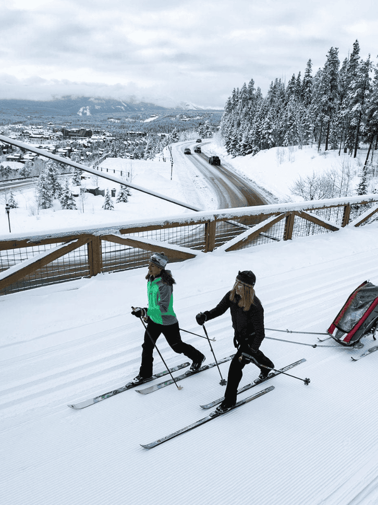 Snowy mountain highway with skiers pulling a sled, scenic winter landscape, QuestForDirections travel guide, winter adventure, travel roads.