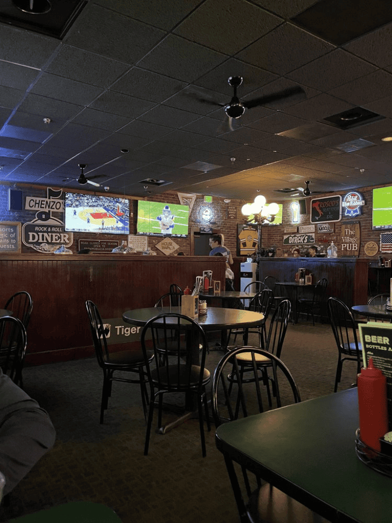 Sports bar with multiple TVs showing football games, dark ceiling, and cozy dining area.