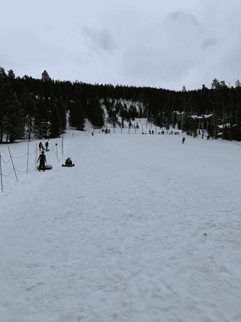 Snowy mountain ski slope with people, trees, and overcast sky at QuestForDirections location.