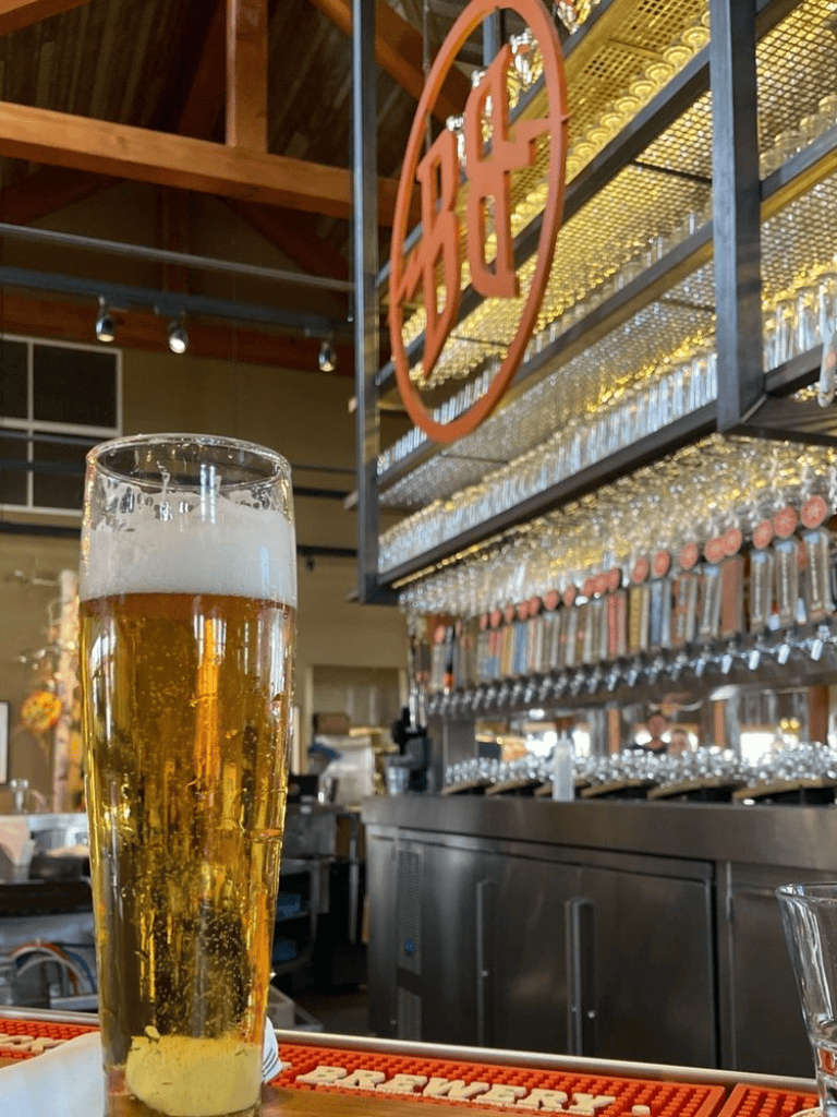 Crisp glass of cold beer at a modern bar with craft beer taps and a cozy brewery ambiance.