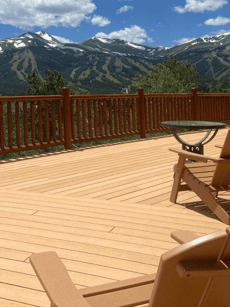 Spectacular mountain view from a wooden deck with outdoor seating and railing, perfect for relaxing and enjoying nature.
