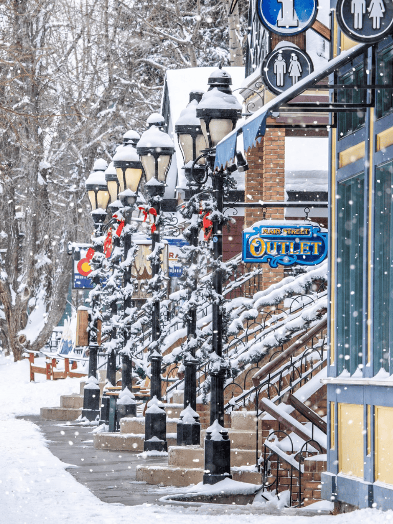 Snow-covered street with lamp posts and outlet sign at QuestForDirections in winter weather.