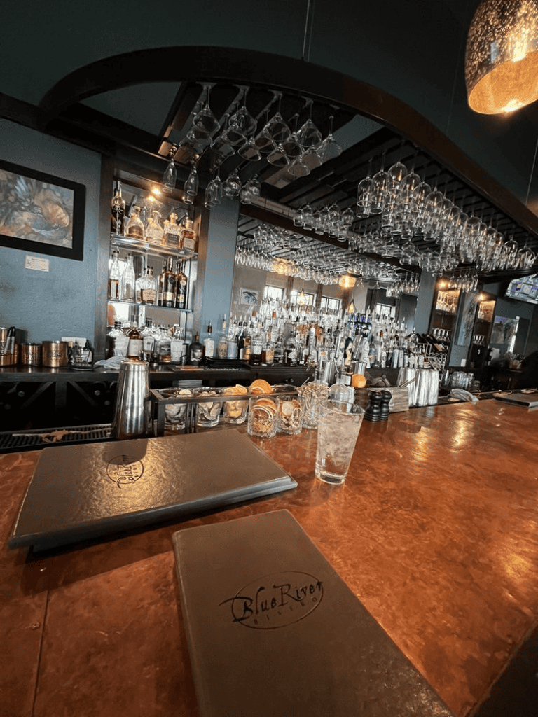 Bright bar with cocktail glasses and liquor bottles on shelves, inviting nightlife atmosphere.
