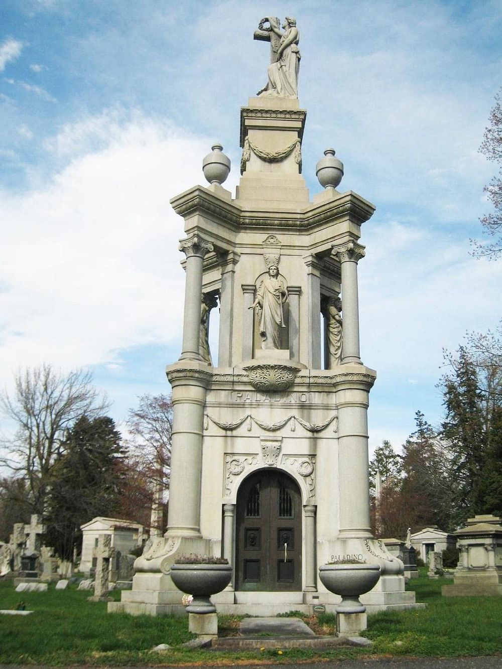 Intricate marble monument with religious statues at a historic cemetery, showcasing elegant architecture and memorial art.