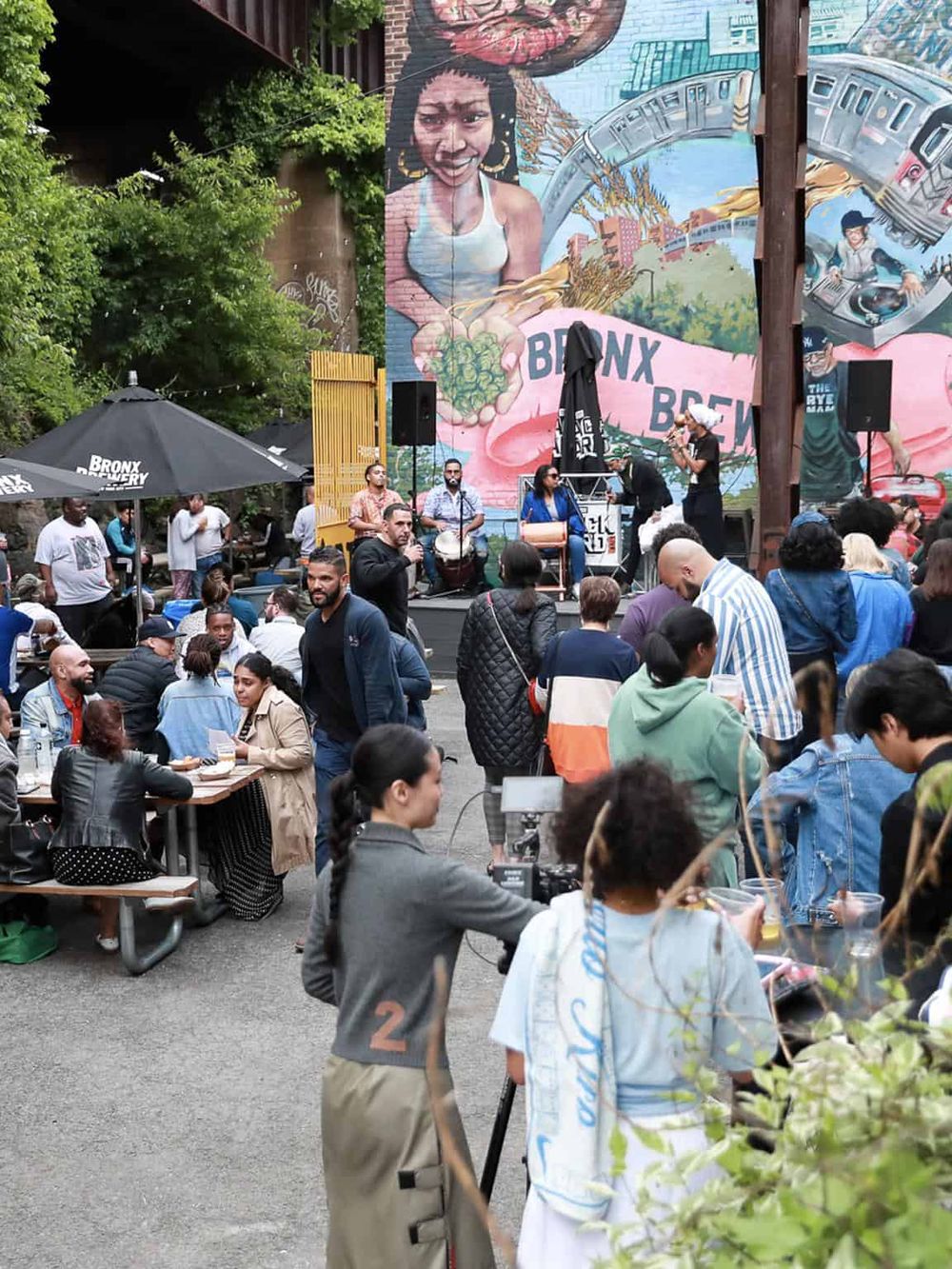 Vibrant outdoor event in Bronx featuring live music, diverse crowd, urban street art mural, and cultural celebration.