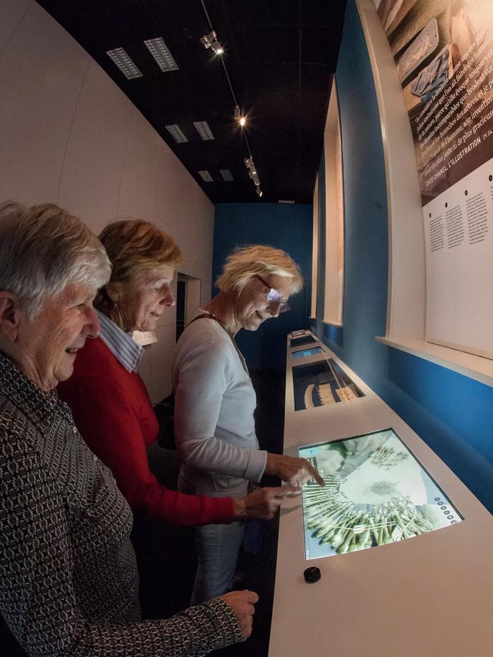 Interactive digital museum exhibit with visitors exploring art and history displays.