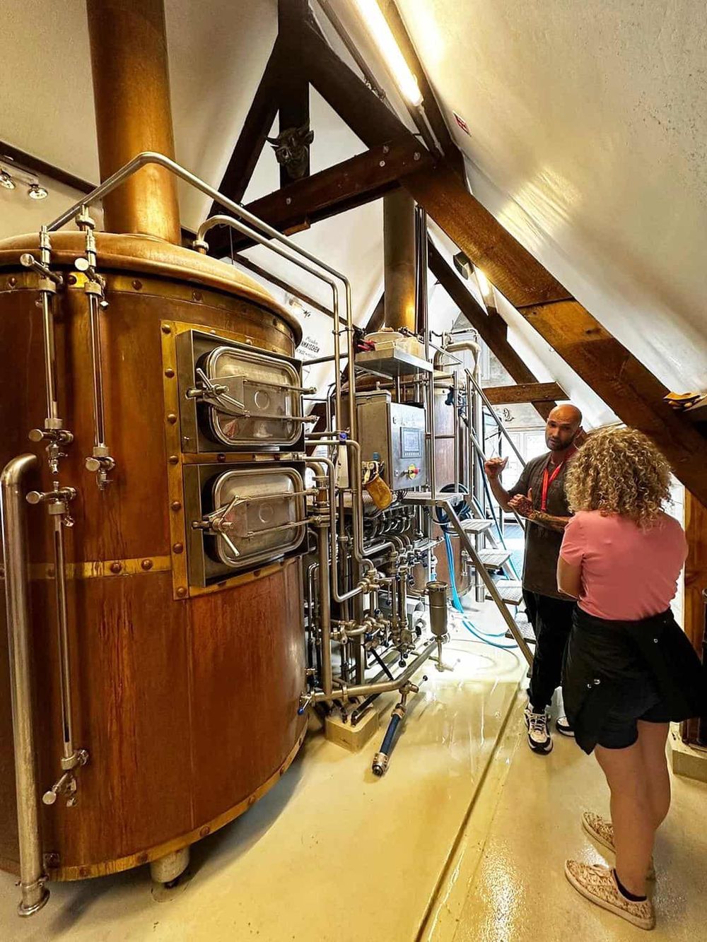 Vintage brewery brewing equipment with two people touring and discussing.