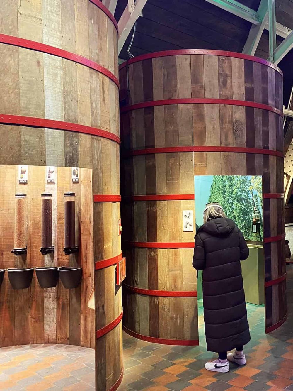 Organic honey dispensers in natural wood barrels at a honey shop, offering a variety of fresh honey flavors for taste testing.