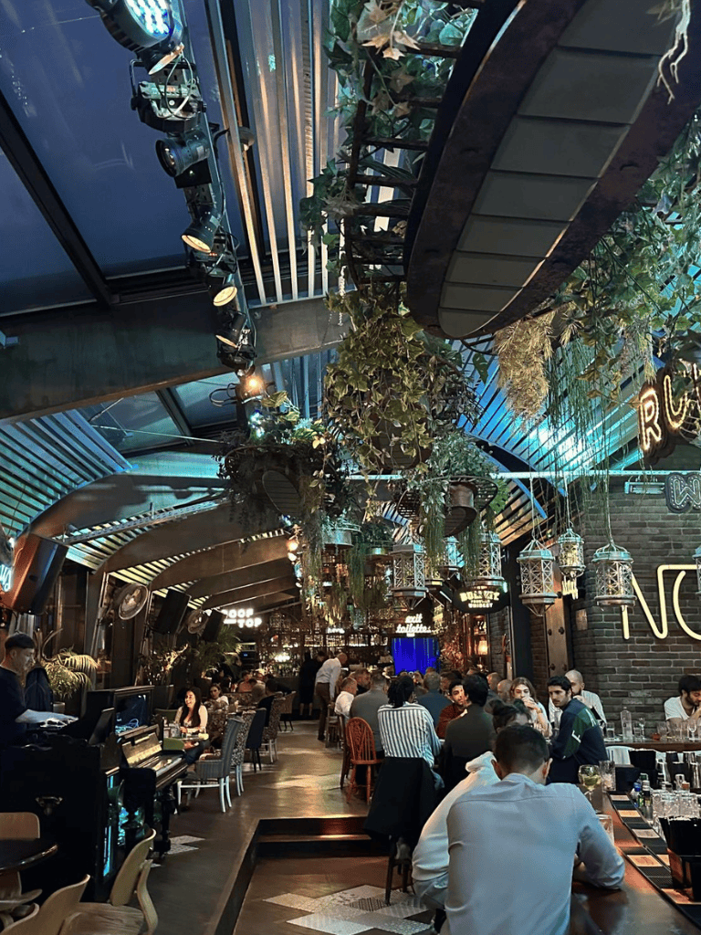 Lush indoor dining area with hanging greenery and elegant lanterns at Quest For Directions restaurant.