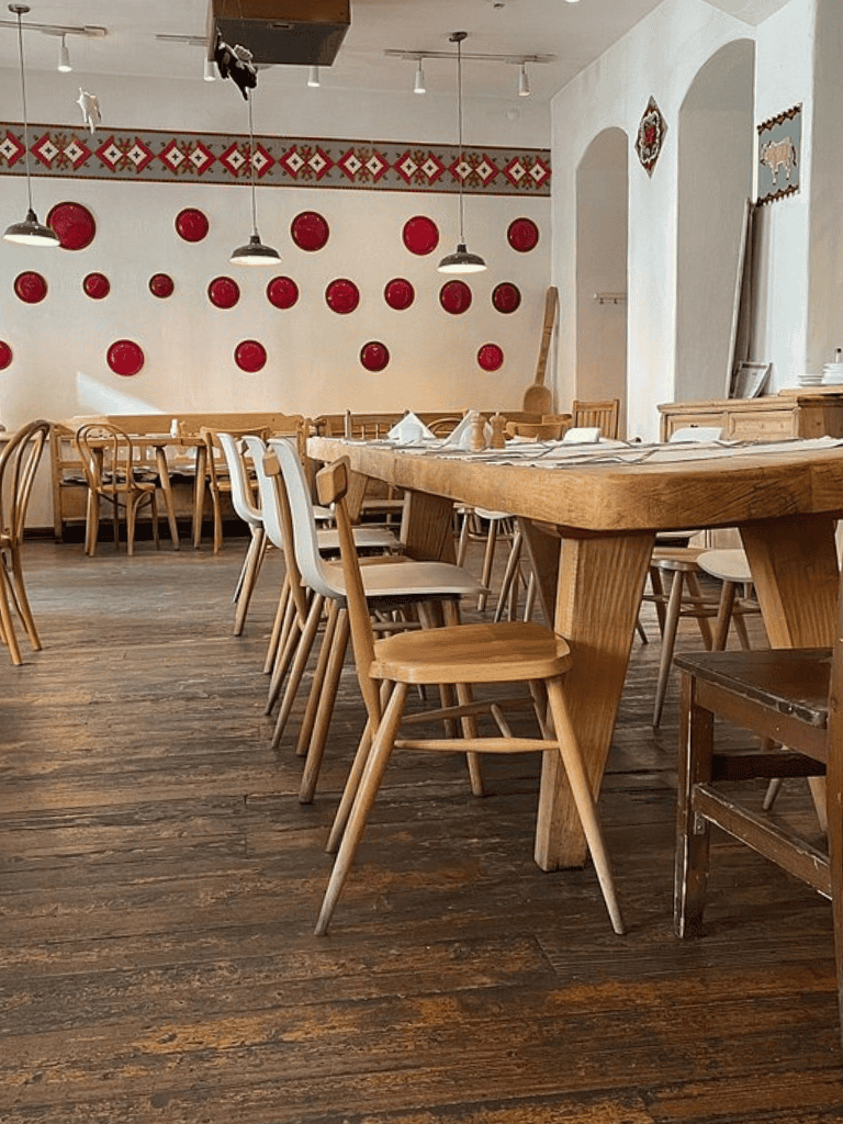 Modern cozy restaurant interior with wooden tables and chairs, rustic wall decor, and warm lighting.